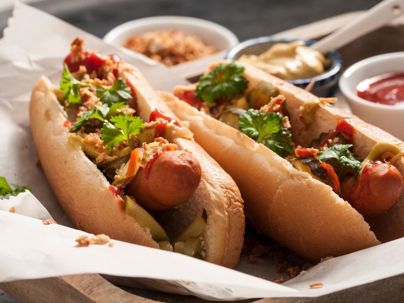 2 Hot Dogs mit selbst gemachter Hot-Dog-Soße und Kräutern und Röstzwiebeln, Nahaufnahme.