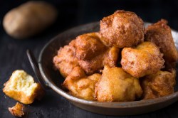 Frittierte Kartoffelkrapfen in einer kleinen Kupferpfanne auf dunklem Untergrund