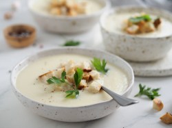 Kohlrabi-Kartoffel-Suppe mit Petersilie und Croûtons in einer gepunkteten weißen Schale.