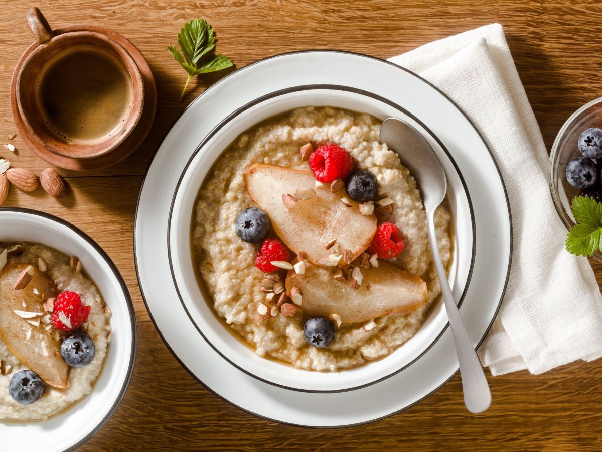 Quinoa-Porridge mit gebackenen Birnen, angerichtet auf einem Teller. Dekoriert mit Beeren.