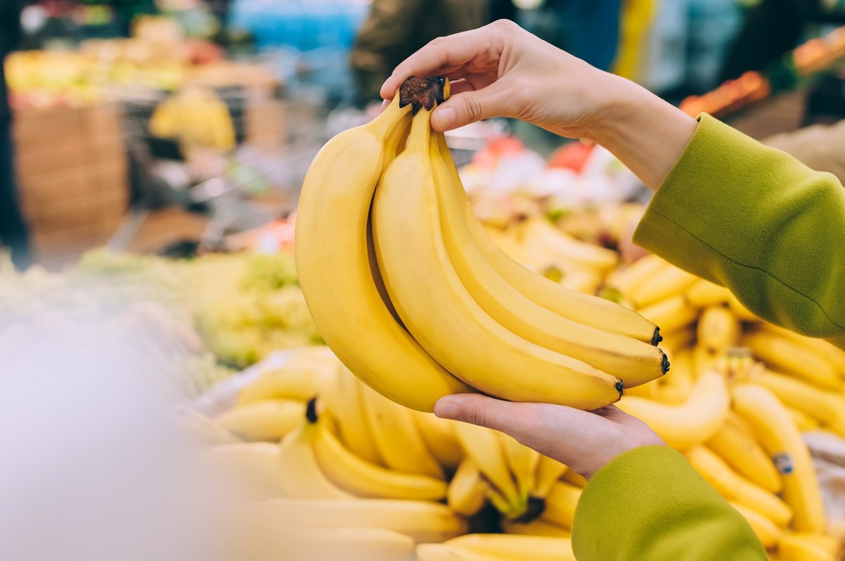 So bleiben Bananen länger frisch: Eine Frau hält ein paar Bananen in der Hand, man sieht nur ihre Hände.