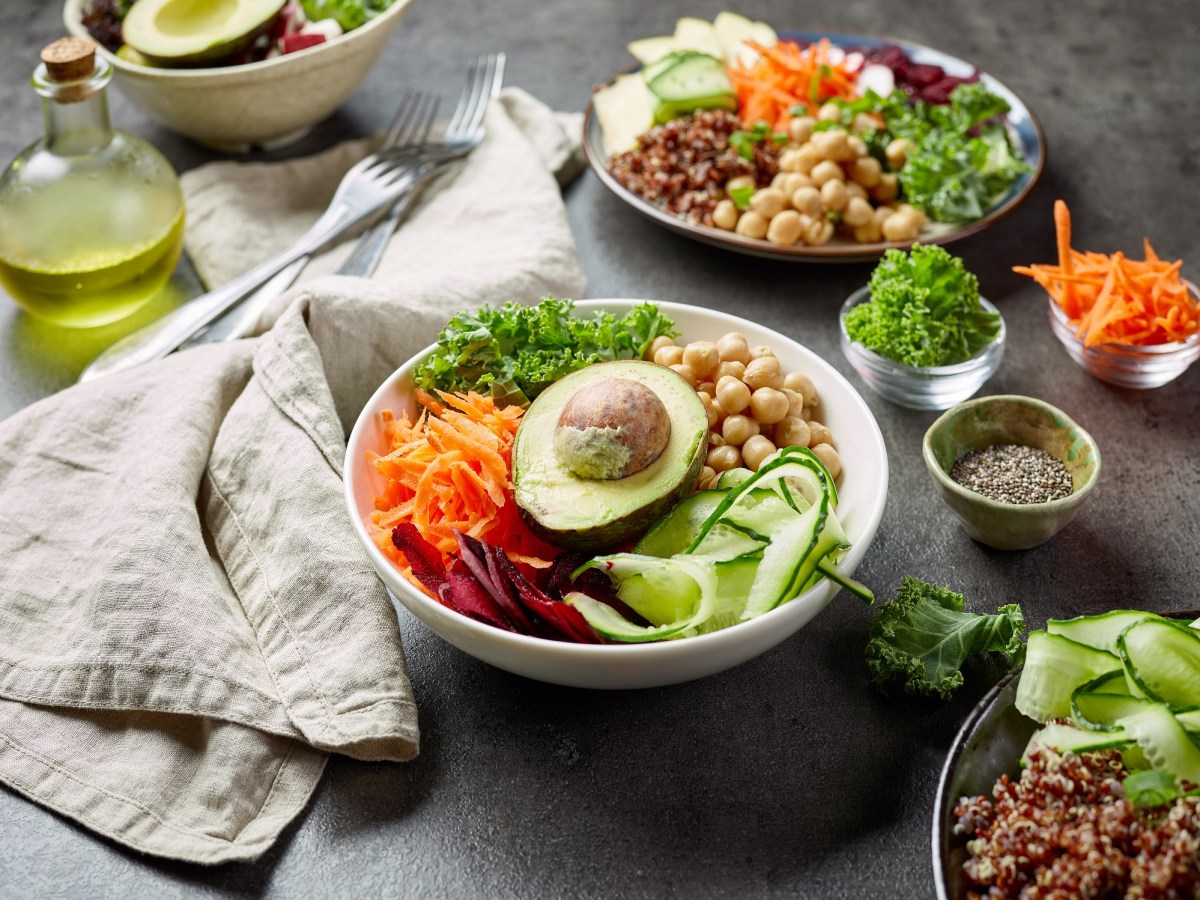 Tipps vegane Ernährung: eine Salatschüssel mit verschiedenen Gemüsesorten wie Avocado und Kartoffel geraspelt, drumherum liegen viele weitere Gemüsesorten.