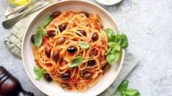 Ein Teller vegane Spaghetti Diavolo mit Oliven und frischem Basilikum.