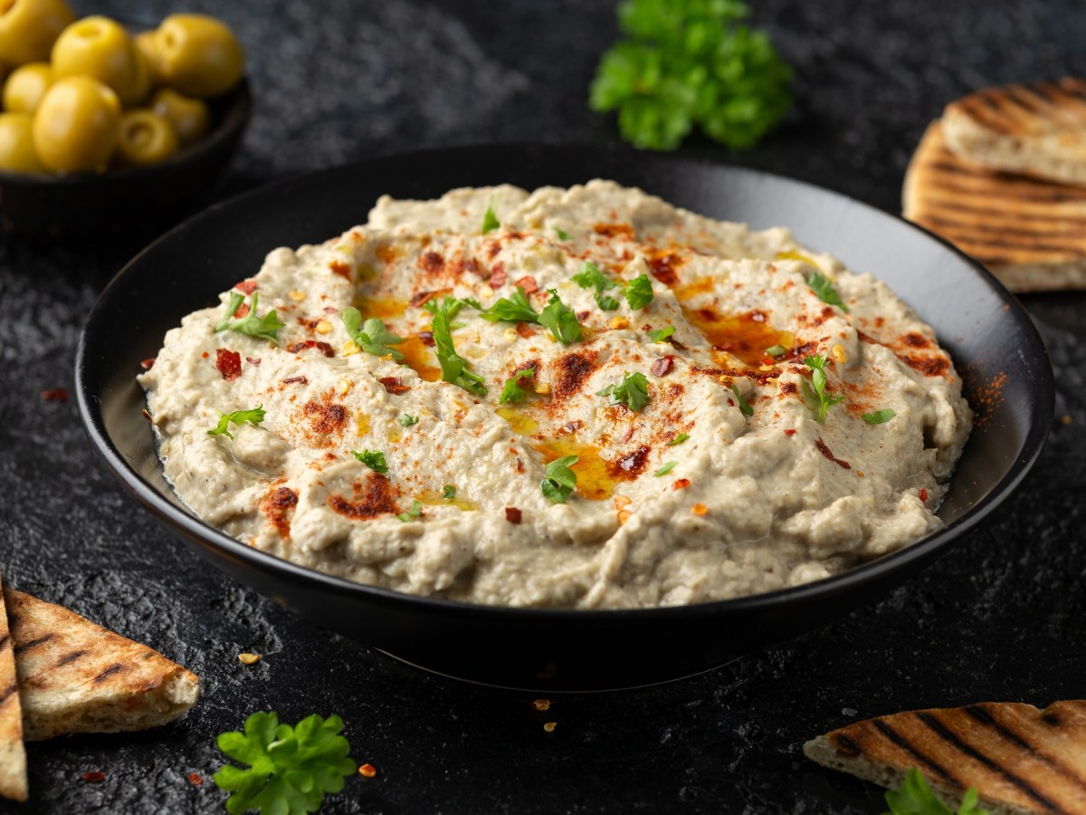 Baba Ganoush in einer schwarzen Schale mit Olivenöl und Petersilie dekoriert