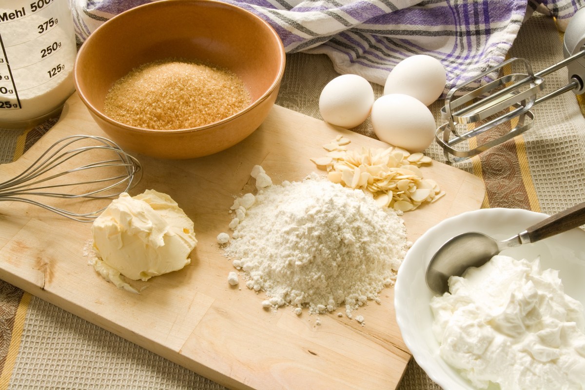 Backmischung aufpeppen: Backutensilien wie Mehl, Butter, Zucker und Eier sowie Rührstäbe eines Handmixers. Nahaufnahme.