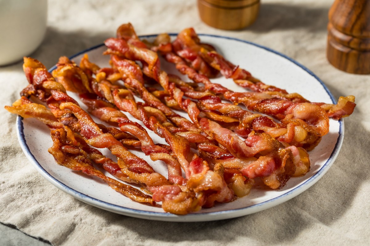 Bacon-Zöpfe auf einem weißen Teller, der auf einer beigen Tischdecke steht.