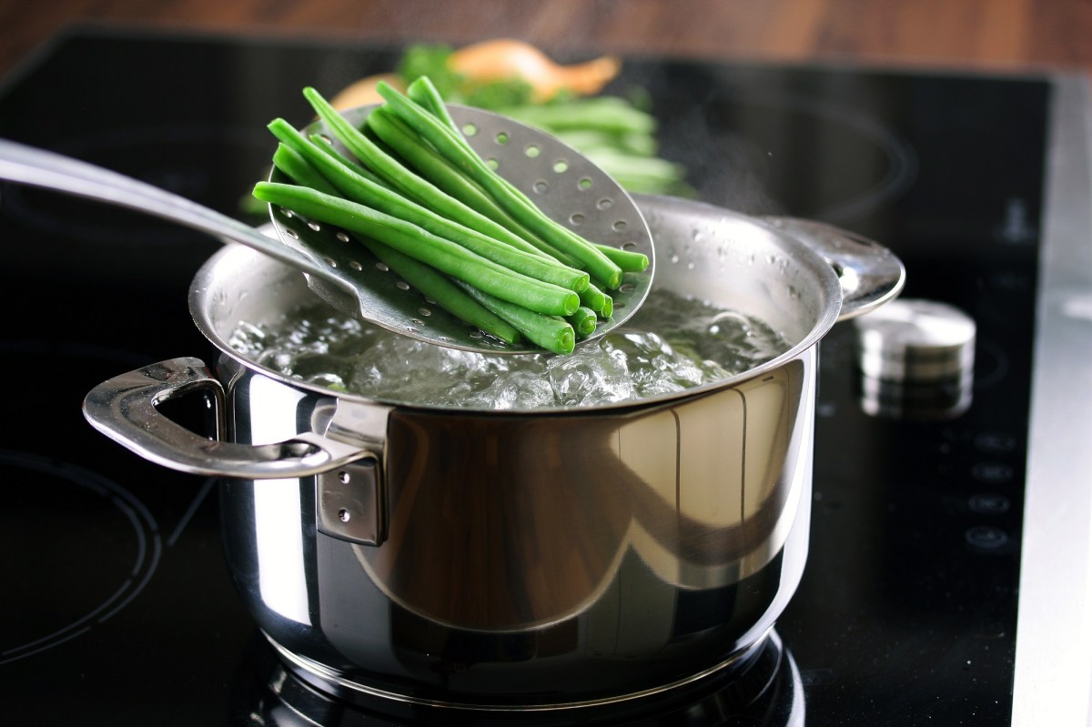 Grüne Bohnen werden nach dem Blanchieren aus dem kochenden Wasser genommen.