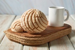 Mexikanische Conchas auf einem Holzbrett neben einer weißen Tasse
