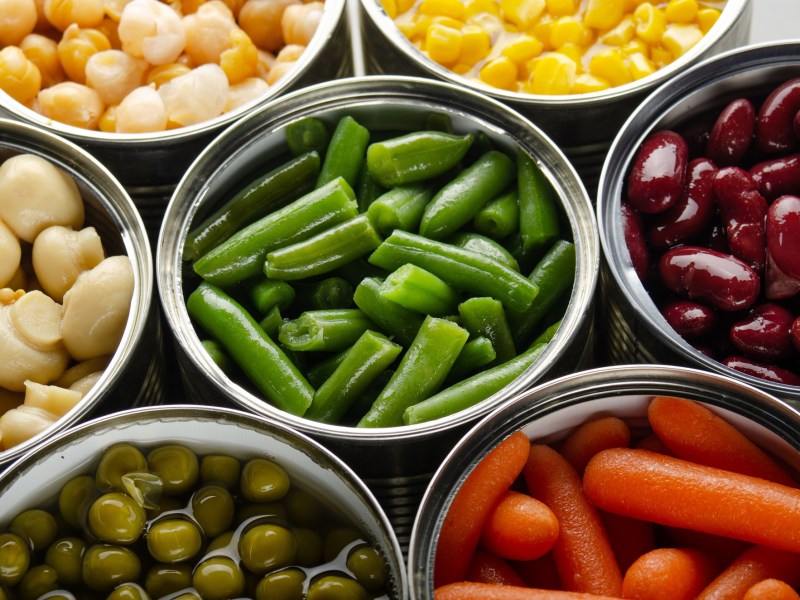 Ist Dosengemüse ungesund: mehrere Konservendosen mit Gemüse und anderen Lebensmitteln in der Draufsicht.
