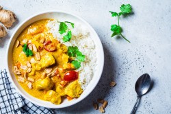 Schüssel mit Reis und Erdnuss-Curry auf einem Tisch.