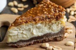 Ein Stück Erdnussbutter-Cheesecake mit Schoko-Karamell-Erdnussbelag.