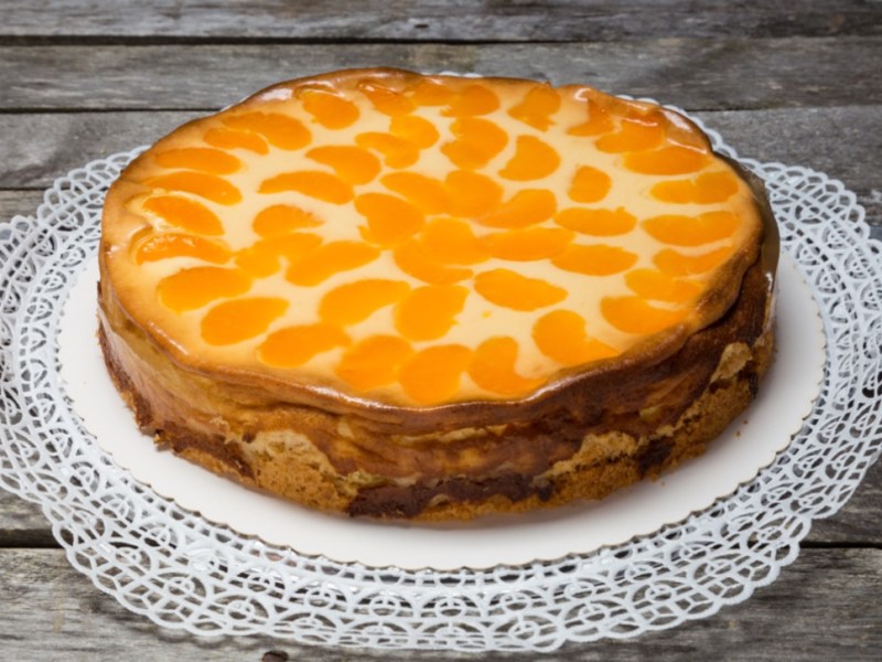 Ein Faule-Weiber-Kuchen mit Mandarinen auf einer Kuchenplatte.