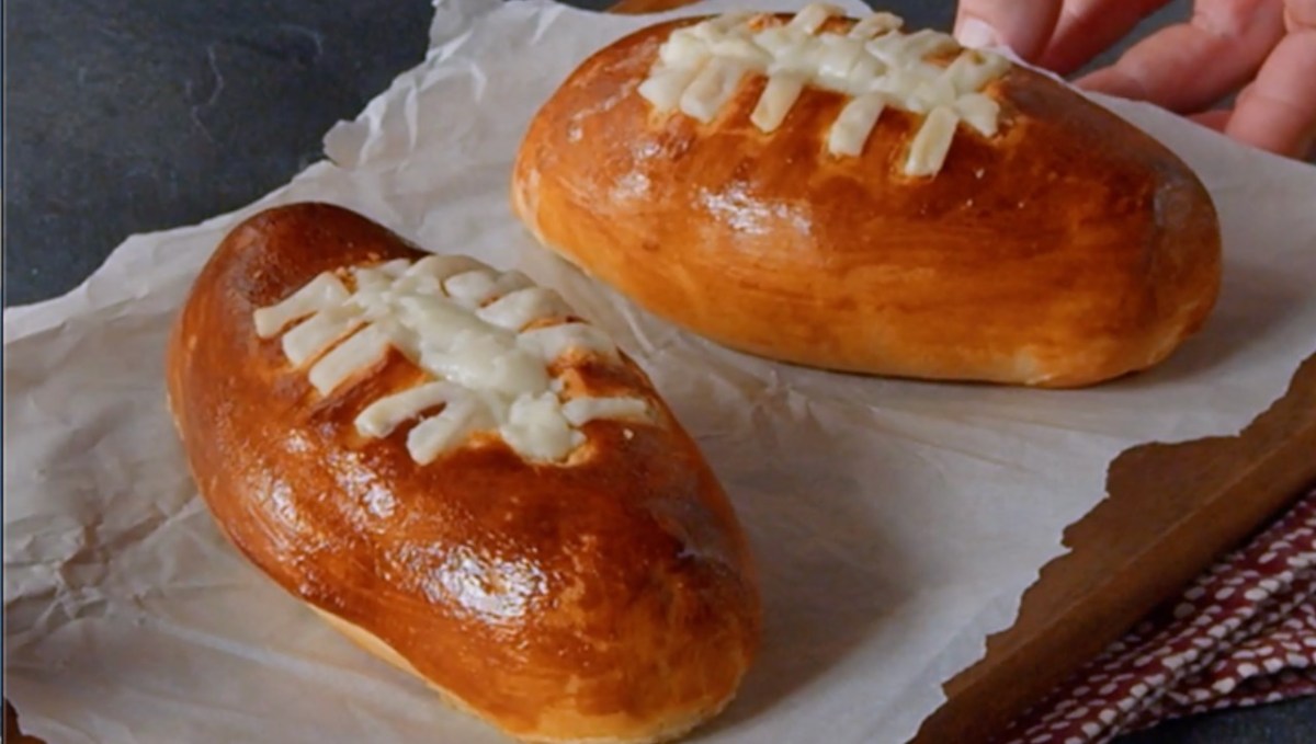 Zwei Football-Snacks mit Käsefüllung auf Backpapier.