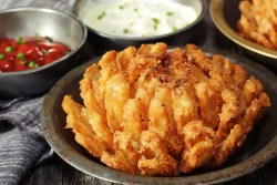 Frittierte Zwiebelblume in einer braunen Schale, serviert mit Dips.