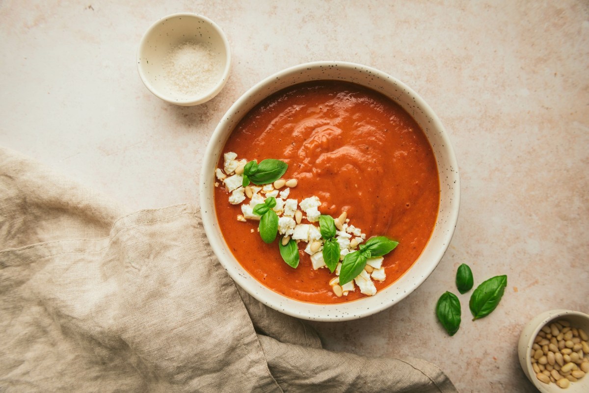 Griechische Tomatensuppe mit Feta in einer Schüssel, garniert mit Feta, Pinienkernen und Basilikum, Draufsicht.