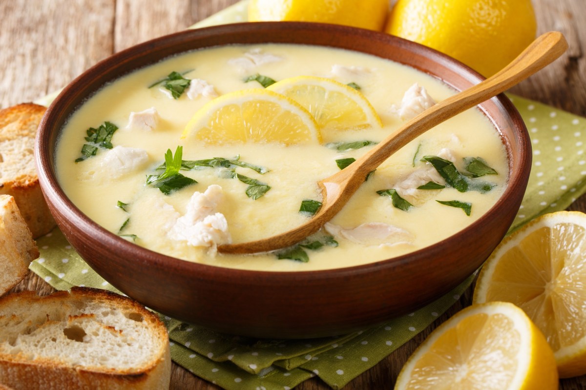 Eine Schale mit gelber Zitronensuppe, Löffel und Zitronenscheiben als Deko