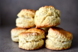 Klassische Scones übereinandergestapelt auf einem dunklen Untergrund.