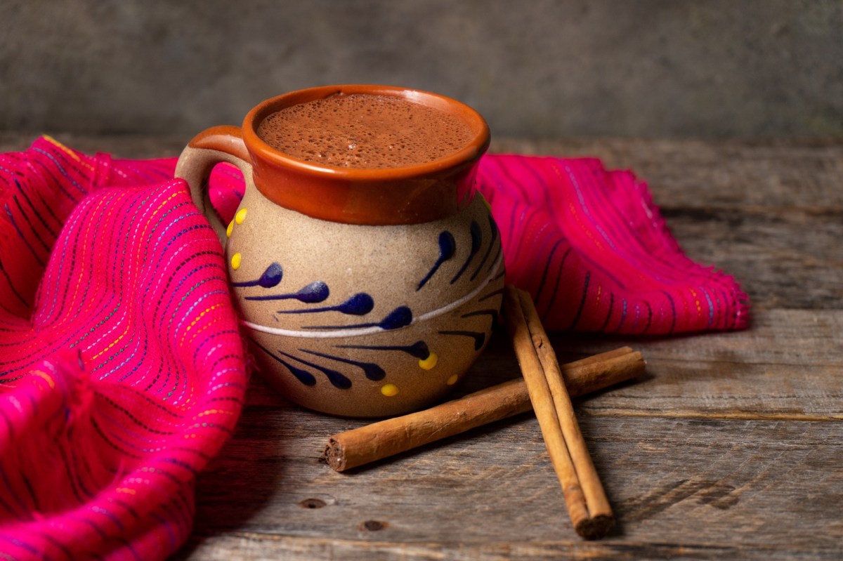 Mexikanische heiße Schokolade in einer traditionellen Tasse mit Zimtstangen.