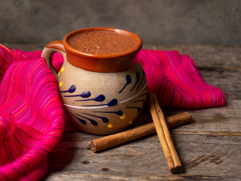 Mexikanische heiße Schokolade in einer traditionellen Tasse mit Zimtstangen.