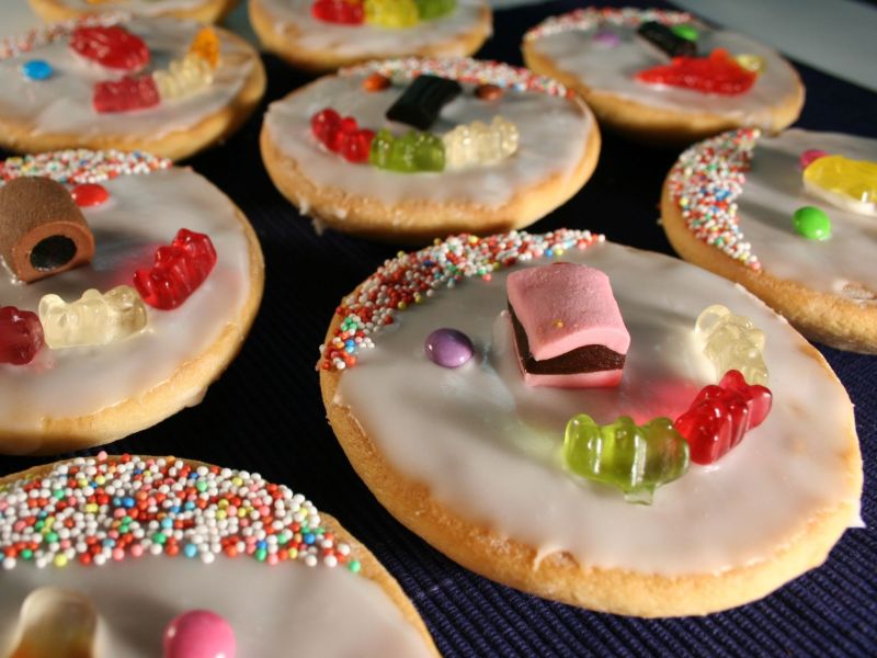 Ein Blech voller Mini-Amerikaner mit Zuckerguss und Süßigkeiten verziert.