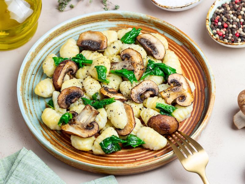 One-Pot-Gnocchi mit Pilzen und Spinat, hübsch angerichtet auf einem Teller.