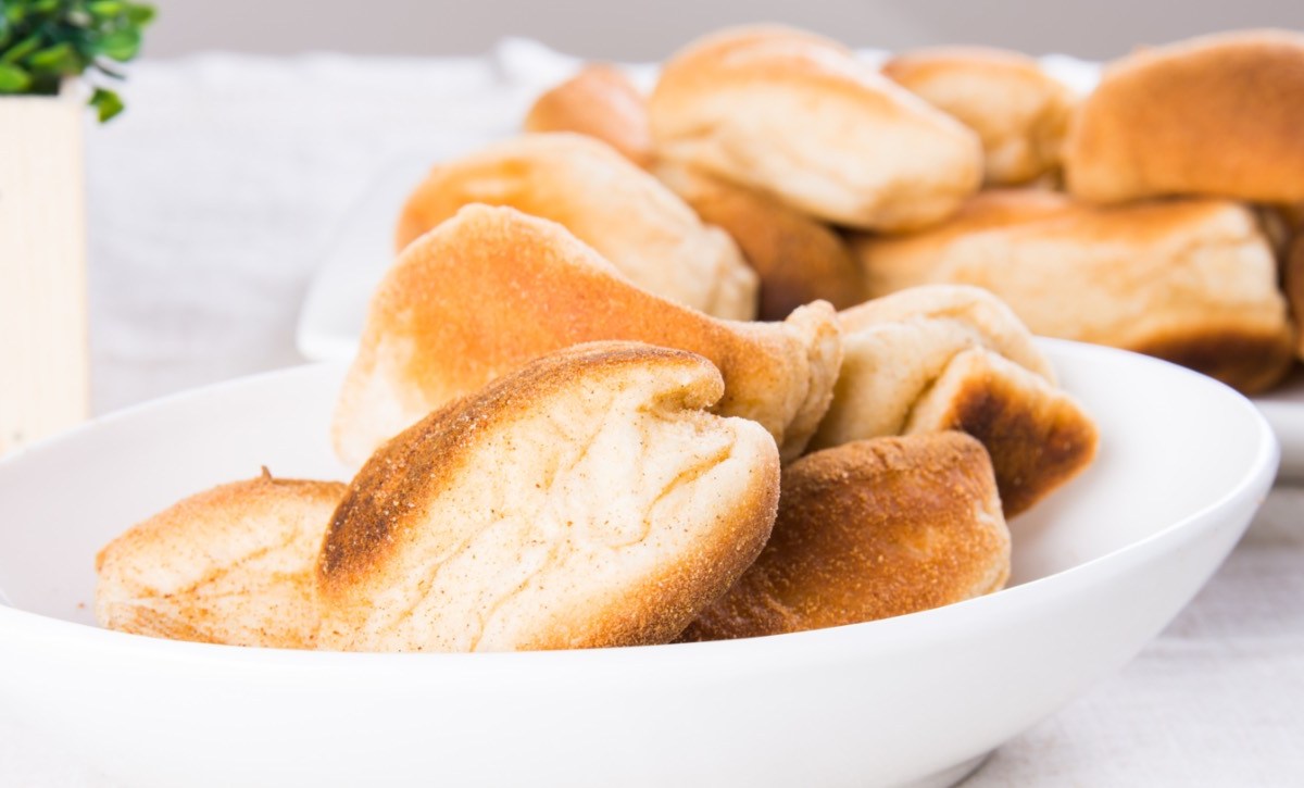 Ein Stapel Pan de Sal in einer Schüssel. Im Hintergrund sind mehr zu sehen.