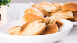 Ein Stapel Pan de Sal in einer Schüssel. Im Hintergrund sind mehr zu sehen.