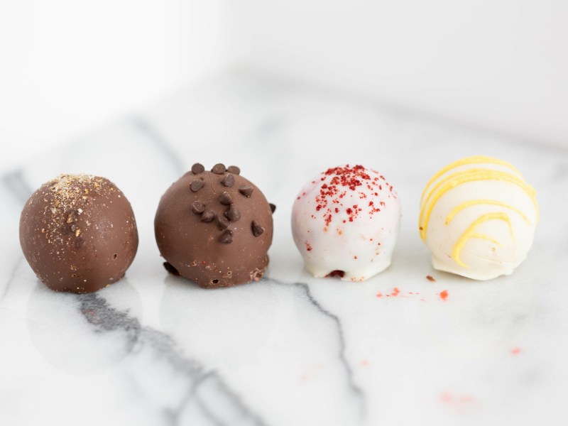 4 Red-Velvet-Pralinen mit Schokoladenüberzug auf einer weißen Marmorplatte.