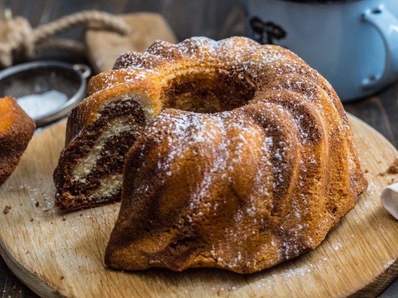 5-Minuten-Kuchen auf einem runden Holzbrett. Ein Stück wurde bereits aus dem Kuchen geschnitten.