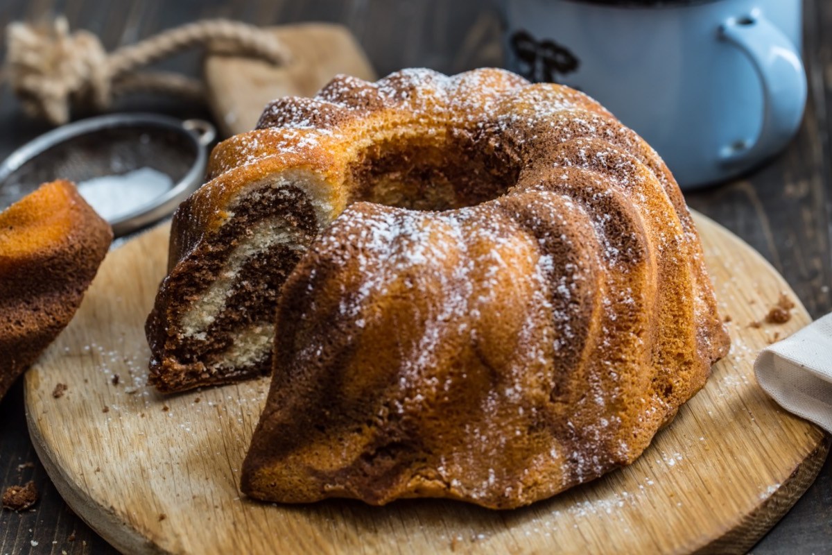 5-Minuten-Kuchen auf einem runden Holzbrett. Ein Stück wurde bereits aus dem Kuchen geschnitten.