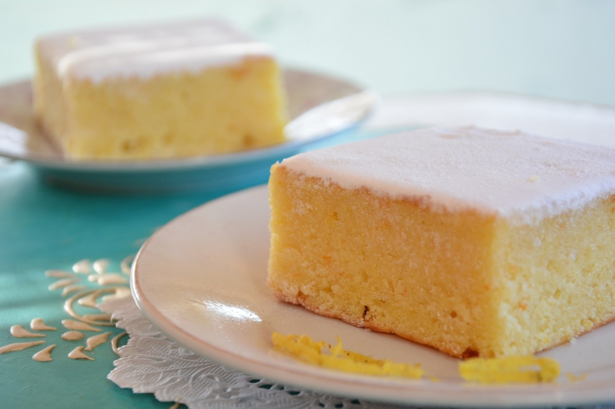 zwei Stück Buttermilchkuchen mit Zitrone auf je einem Teller, garniert mit Zuckerguss.