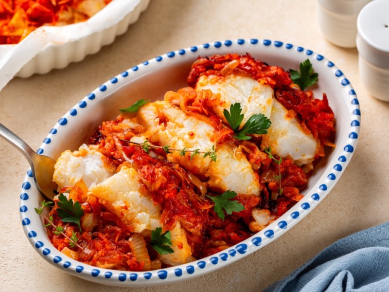 Griechischer Fischauflauf mit Tomaten und Feta in Auflaufform in der Draufsicht.