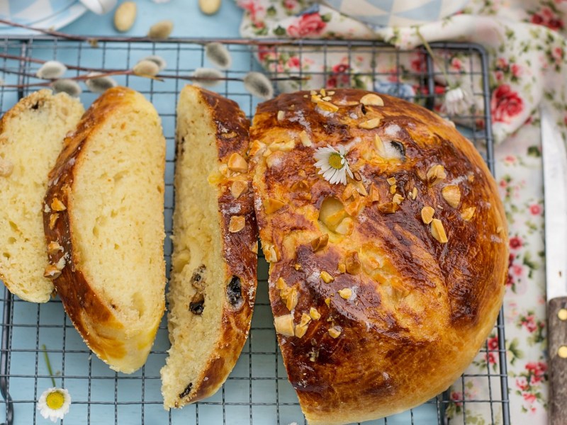 Kuchenrost mit angeschnittenem Osterbrot mit Mandeln und Rosinen.