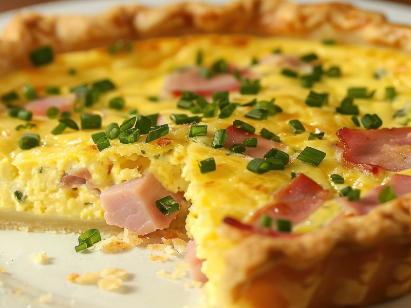 Angeschnittene Oster-Quiche mit Schinken und Ei.