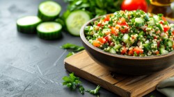 Schale mit Petersiliensalat, Tomaten und Gurke auf Holzbrett und dunklem Untergrund