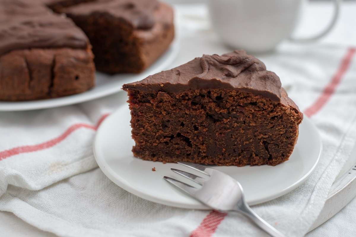 Teller mit einem Stück Rote-Bete-Kuchen auf weißem Tischtuch mit roten streifen