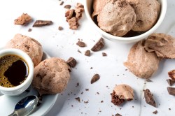 Ein weißer Untergrund mit Schokoladen-Baisers und einer Tasse Kaffee