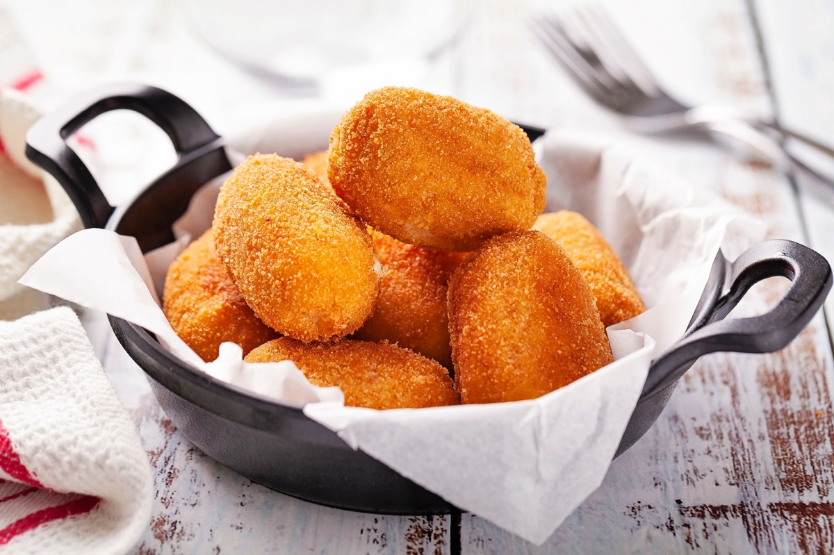 Spanische Kroketten in einem gusseisernen Topf auf einem Holztisch.