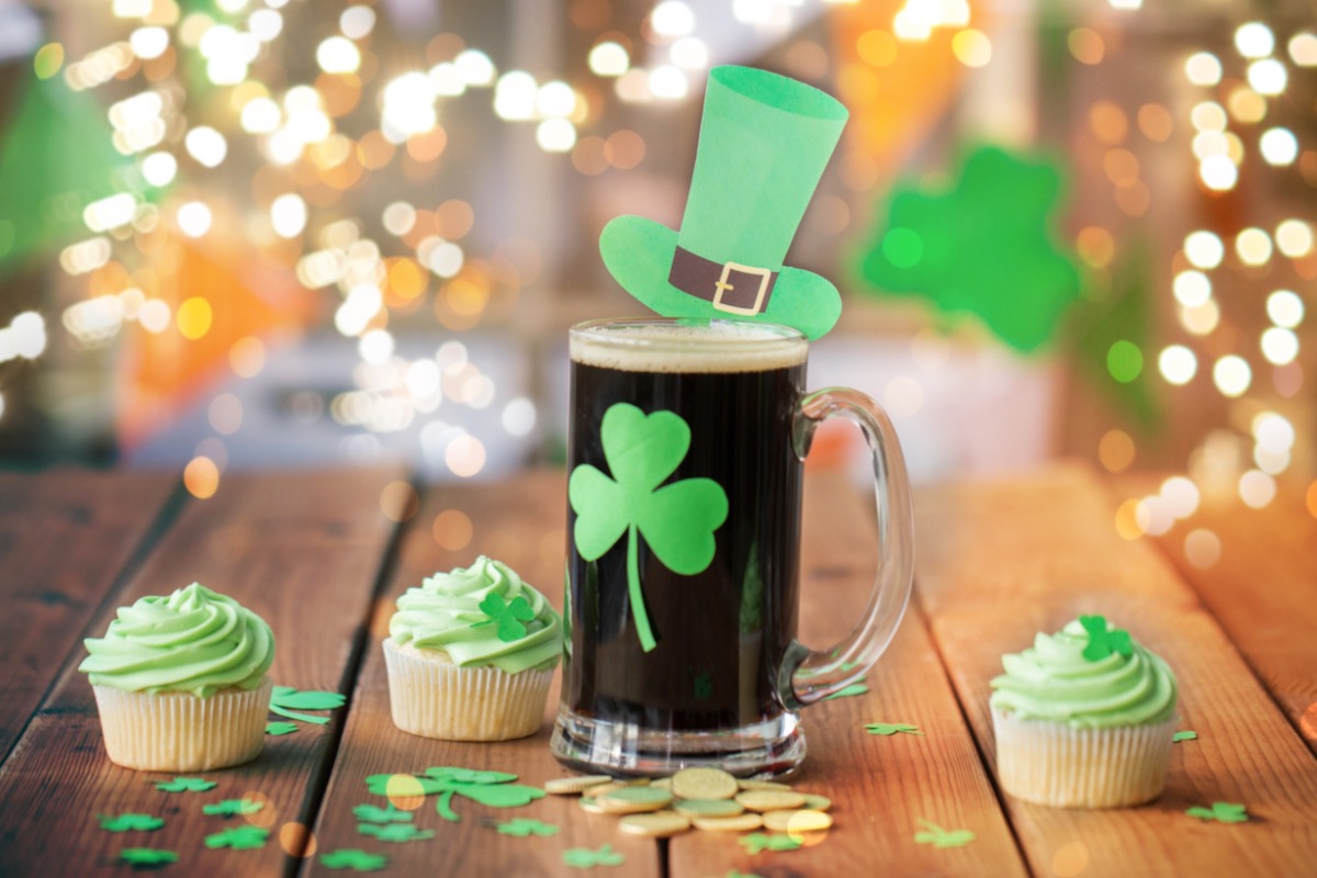 Rezepte St. Patrick's Day: Ein Guinness mit Kleeblatt auf dem Glas und mehrere grüne Cupcakes.