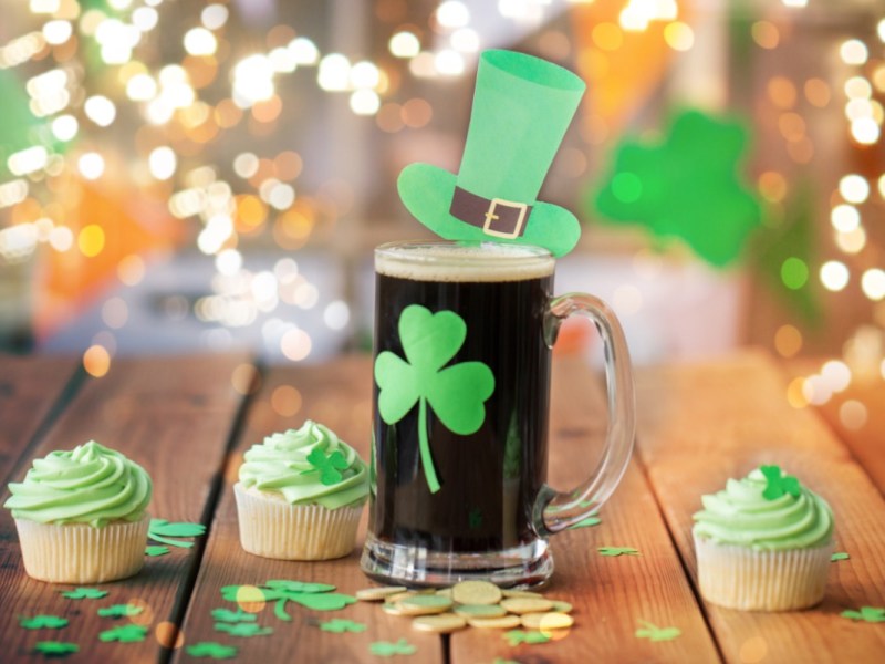 Rezepte St. Patrick's Day: Ein Guinness mit Kleeblatt auf dem Glas und mehrere grüne Cupcakes.