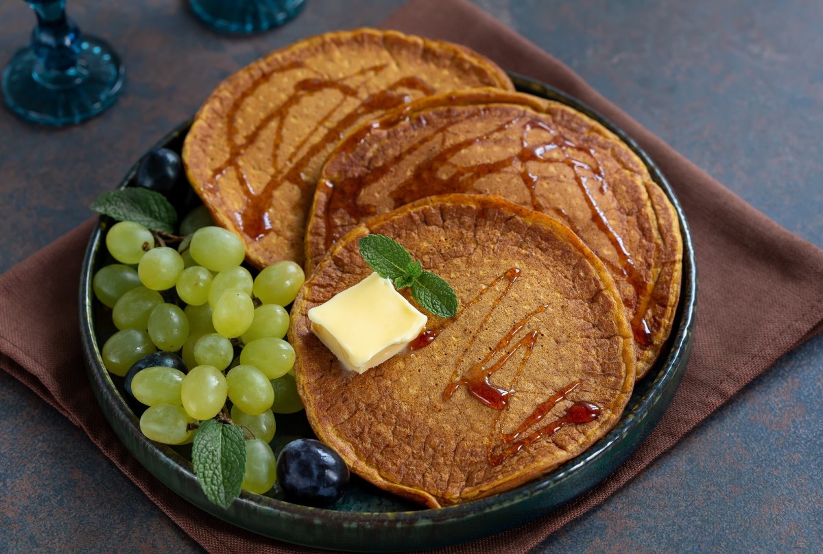 Süßkartoffel-Pancakes mit Butter und Weitrauben auf dunklem Teller