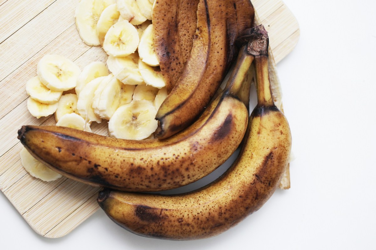 Versteckter Alkohol in Lebensmitteln: zwei überreife Bananen auf einem Holzbrett, daneben weitere Bananenschalen und Bananenscheiben.