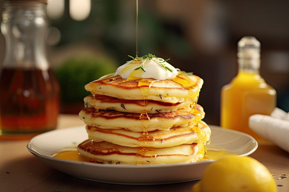 Teller mit einem Stapel Zitronen-Ricotta-Pancakes auf Holztisch.