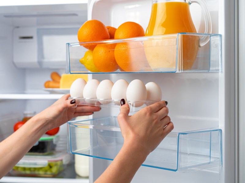 Frau holt frische Eier aus dem Kühlschrank