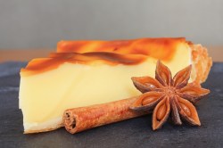 Ein Stück vom Flan pâtissier, dekoriert mit einer Stange Zimt und Sternanis.