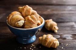 Kartoffel-Croissants mit Käsefüllung in einer Schüssel, zwei Stück liegen daneben.