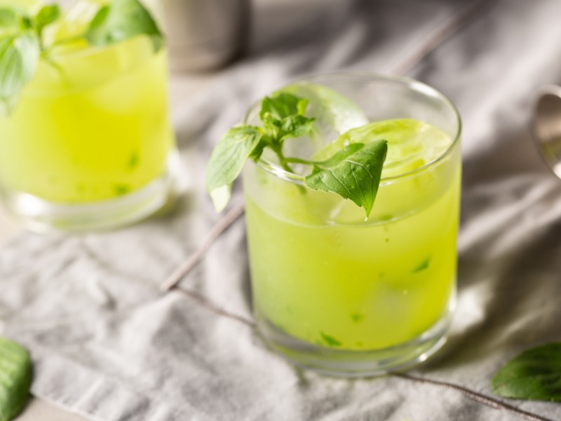 Zwei Gläser Gin Basil Smash auf grauem Untergrund