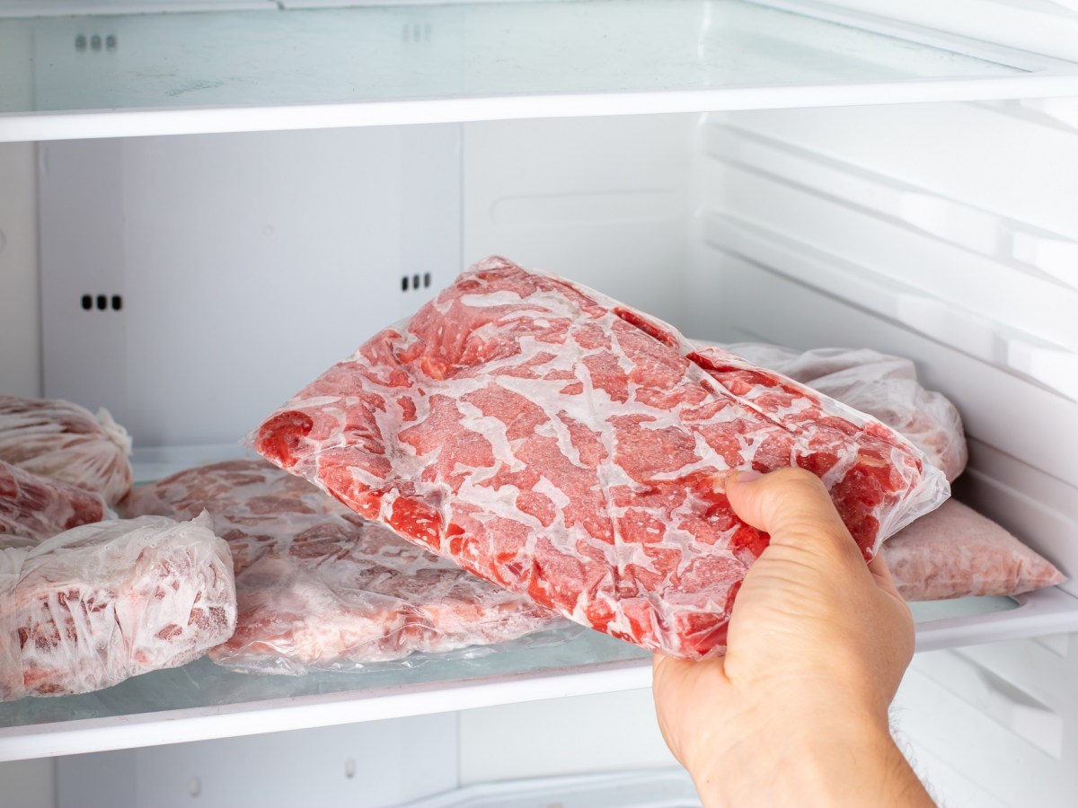 Hackfleisch einfrieren: eine Hand legt eine Packung Hackfleisch ins Gefrierfach