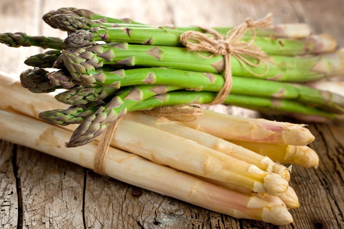 Grüner oder weißer Spargel gesünder: Ein Bund grüner Spargel liegt auf einem Bund weißem Spargel.