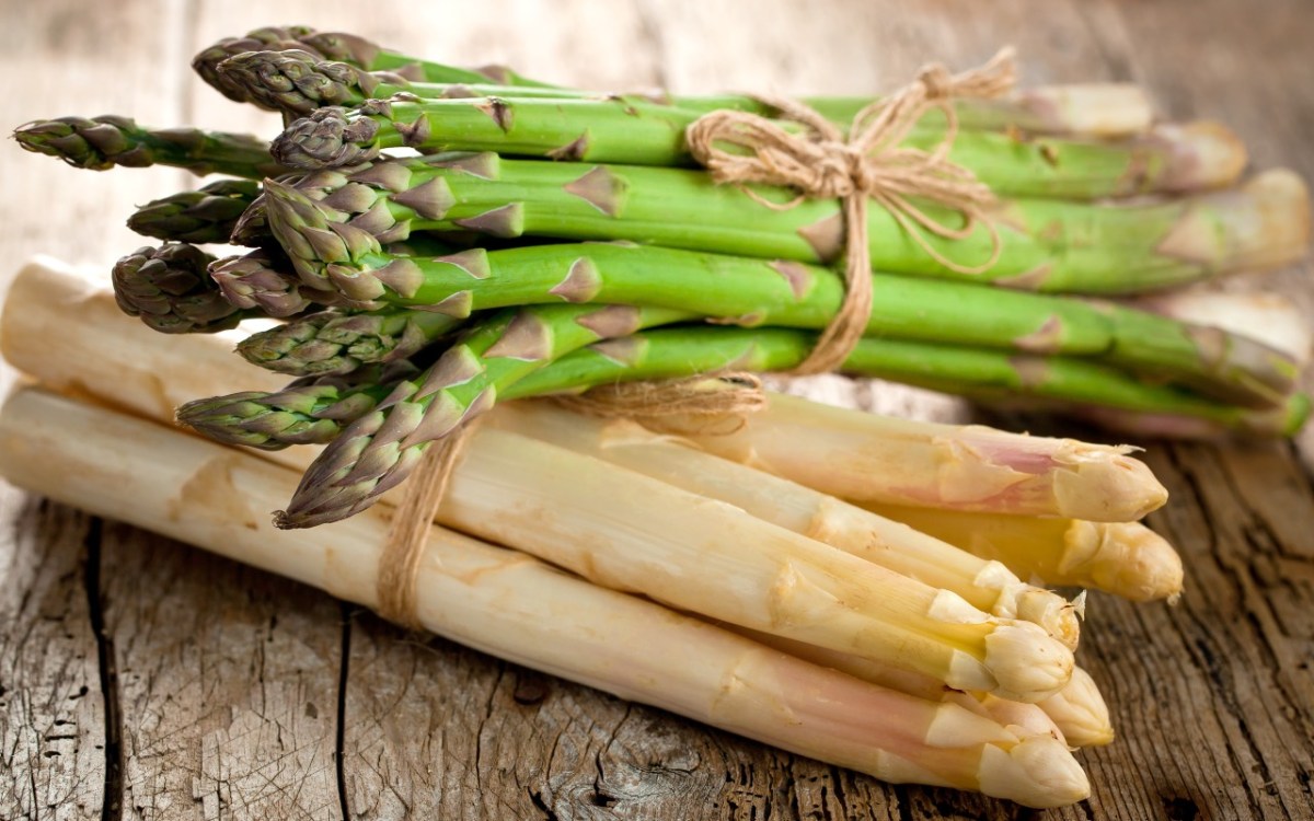 Grüner oder weißer Spargel gesünder: Ein Bund grüner Spargel liegt auf einem Bund weißem Spargel.